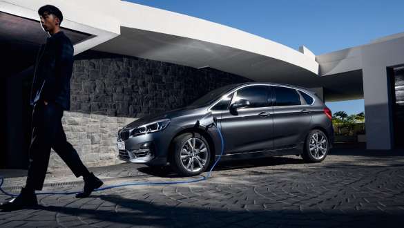 BMW 225xe Active Tourer F45 ibrida Plug-in vista laterale a tre quarti davanti ad un edificio BMW 225xe Active Tourer F45 ibrida Plug-in vista laterale a tre quarti davanti ad un edificio con fotomodella