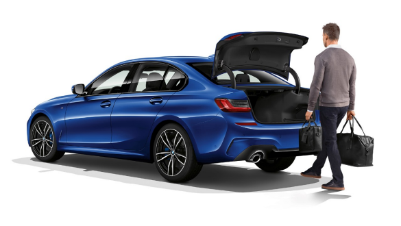 BMW Serie 3 Berlina, attivazione automatica del portellone Inquadratura posteriore a tre quarti della BMW Serie 3 Berlina con guidatore che attiva l’apertura automatica del portellone con un piede.
