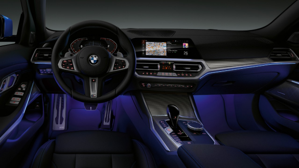BMW Serie 3 Berlina, Ambient Light Vista anteriore del cockpit lato guida della BMW Serie 3 Berlina con vano piedi illuminato in blu dall’Ambient Light.