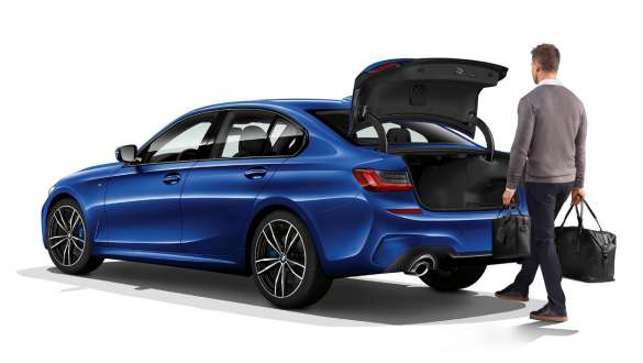 BMW Serie 3 Berlina (G20), azionamento automatico portellone posteriore Vista posteriore a tre quarti della BMW Serie 3 Berlina (G20) con guidatore che apre automaticamente il portellone posteriore con il piede.
