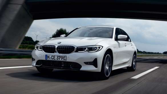 BMW Serie 3 Berlina ibrida Plug-in 2021 G20 Vista anteriore a tre quarti in ricarica BMW Serie 3 Berlina ibrida Plug-in 2021 G20 Vista anteriore a tre quarti in movimento su strada