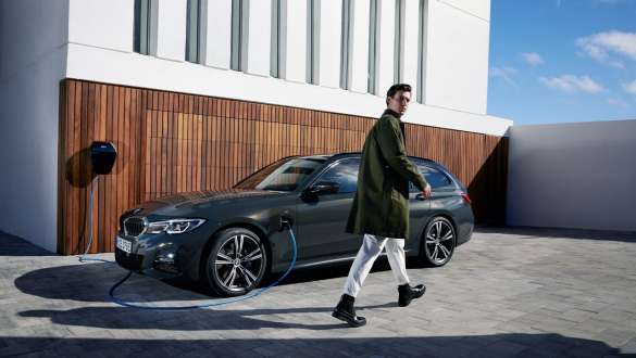 BMW Serie 3 Touring ibrida Plug-in 2021 G21 Vista laterale a tre quarti in ricarica BMW Serie 3 Touring ibrida Plug-in 2021 G21 Vista laterale a tre quarti con modella
