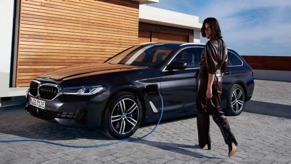 BMW Serie 5 Touring ibrida Plug-in 2021 G31 Vista laterale a tre quarti in ricarica BMW Serie 5 Touring ibrida Plug-in 2021 G31 Vista laterale a tre quarti in ricarica con modella