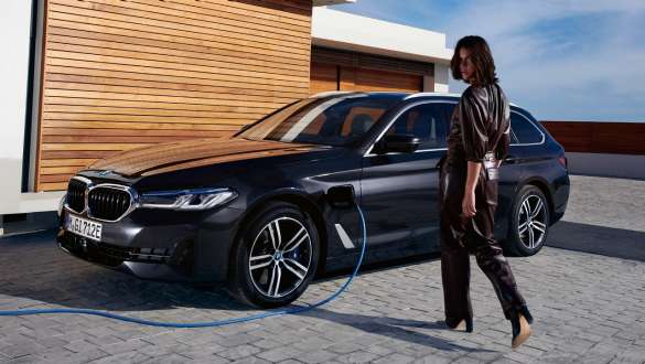 BMW Serie 5 Touring ibrida Plug-in 2021 G31 Vista laterale a tre quarti in ricarica BMW Serie 5 Touring ibrida Plug-in 2021 G31 LCI Vista laterale a tre quarti in ricarica con fotomodella