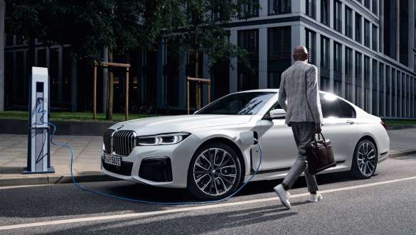 BMW 745e Berlina ibrida Plug-inG11 G12 Mineral White metallizzato vista laterale a tre quarti in ricarica BMW 745e Berlina ibrida Plug-inG11 G12 Mineral White metallizzato Vista laterale a tre quarti in ricarica con modella