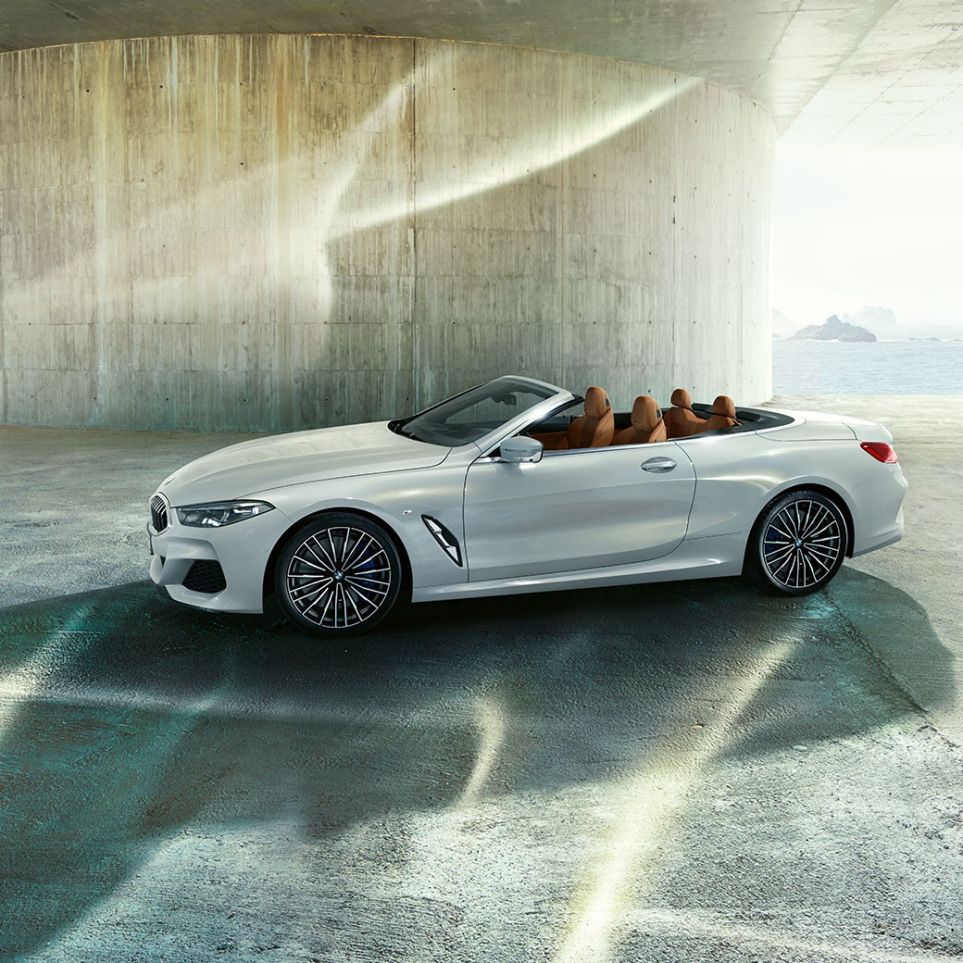 Nuova BMW M850i xDrive in Mineral White metallic, vista laterale con capote in tessuto aperta G14. Nuova BMW M850i xDrive in Mineral White metallic, vista laterale con capote in tessuto aperta G14.