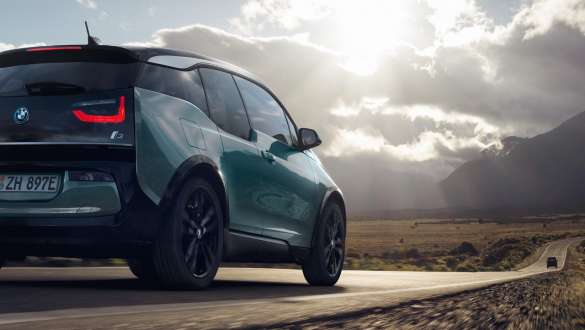 BMW i3 2018 vista posteriore a tre quarti in viaggio su una strada provinciale I01 BMW i3 Jucaro Beige con profilo in Frozen Grey metallizzato vista posteriore a tre quarti in viaggio su una strada provinciale I01
