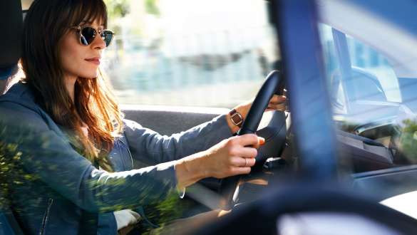 Una signora con occhiali da sole guida una BMW i3 Una signora con occhiali da sole guida una BMW i3