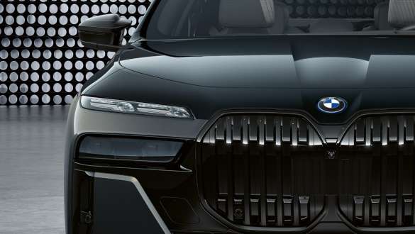 Marcata configurazione frontale della BMW M760e xDrive Berlina G70 Primo piano del cofano motore e della calandra a doppio rene con logo M della BMW M760e xDrive Berlina G70 in bicolore BMW Individual Sapphire Black metallizzato e BMW Individual Dravit Grey metallizzato