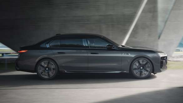 Autonomia elettrica della BMW M760e xDrive Berlina G70 Pacchetto M Performance Autonomia elettrica della BMW M760e xDrive Berlina G70 con Pacchetto M Performance, vernice bicolore BMW Individual Sapphire Black metallizzato e BMW Individual Dravit Grey metallizzato in vista laterale in movimento su strada