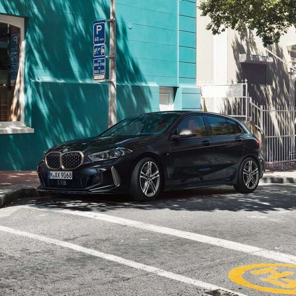 BMW M135i xDrive, vista laterale a tre quarti F40. BMW M135i xDrive in Sapphire Black metallizzato, vista laterale a tre quarti, mentre sta parcheggiando F40.