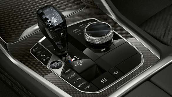 Interni della BMW X6 M50i con primo piano della leva cambio con logo M. Leva del cambio con logo M.