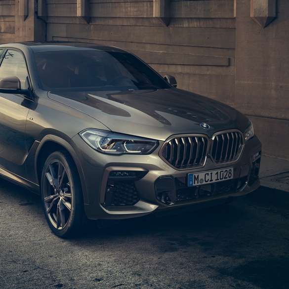 BMW X6 M50i ferma. Vista anteriore a tre quarti ferma della BMW X6 M50i in ambiente urbano.