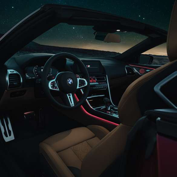 BMW M8 Competition Cabrio, cockpit F91. BMW M8 Competition Cabrio, cockpit di notte con volante in pelle M e luce ambiente rossa F91.