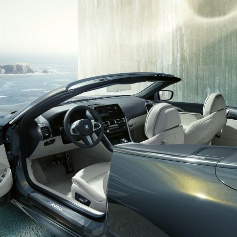 BMW M850i xDrive Cabrio, interni G14. BMW M850i xDrive Cabrio in Dravit Grey metallizzato con capote aperta, interni con volante in pelle M ed equipaggiamento in pelle Merino BMW Individual Ivory White G14.