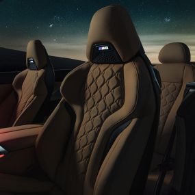 Sedili sportivi M in pelle Merino F91. BMW M8 Competition Cabrio con capote aperta sotto il cielo stellato, abitacolo con sedili sportivi M in pelle Merino e luce ambiente rossa F91.