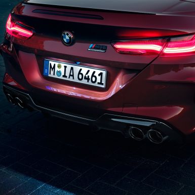 BMW M8 M Competition Cabrio, primo piano del posteriore F91. BMW M8 Competition Cabrio in Motegi Red metallizzato, primo piano del posteriore con gruppi ottici a LED e M8 Competition Badge F91.