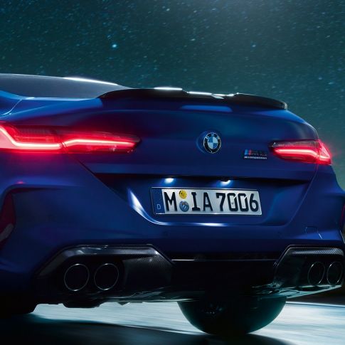 Diffusore M in carbonio nero F92. BMW M8 Competition Coupé in Marina Bay Blue metallizzato, primo piano del posteriore di notte con diffusore M in carbonio nero F92.