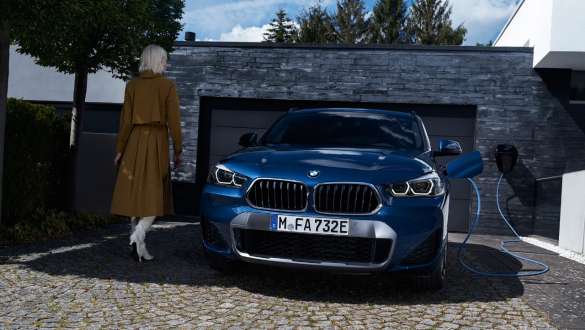 BMW X2 xDrive25e F39 ibrida Plug-in Vista anteriore davanti al garage BMW X2 xDrive25e F39 ibrida Plug-in Vista anteriore davanti al garage con fotomodella