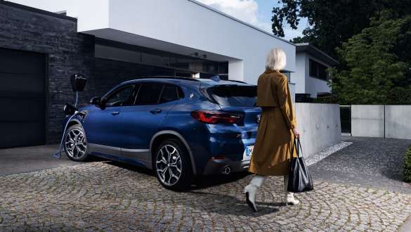 BMW X2 xDrive25e F39 ibrida Plug-in vista posteriore a tre quarti in ricarica BMW X2 xDrive25e F39 ibrida Plug-in vista posteriore a tre quarti in ricarica con fotomodella