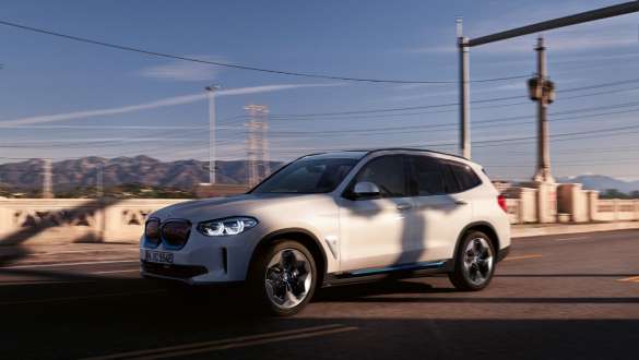 Assetto adattivo M della BMW iX3 SUV G08 in viaggio su strada Assetto adattivo M della BMW iX3 SUV G08 2020 Mineral White metallizzato vista anteriore a tre quarti in movimento su strada