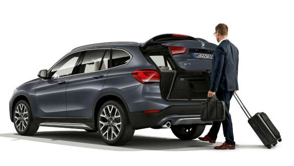 BMW X1, azionamento automatico del portellone posteriore F48 BMW X1, vista laterale da ferma con portellone posteriore aperto. F48