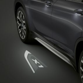 BMW X1, proiezione a LED del logo “X1”. BMW X1, vista laterale con primo piano della proiezione a LED del logo “X1”.