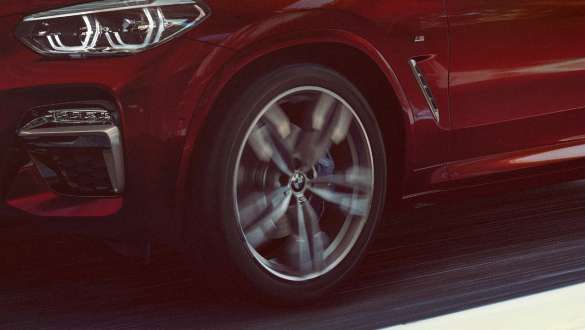 Assetto adattivo M della BMW X4 G02 Assetto adattivo M della BMW X4 M40i G02 2018 Flamenco Red brilliant effect Vista laterale a tre quarti con cerchio in alluminio