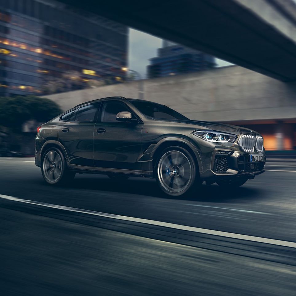 BMW X6 in movimento G06. Vista anteriore a tre quarti in movimento della BMW X6 in ambiente urbano G06.