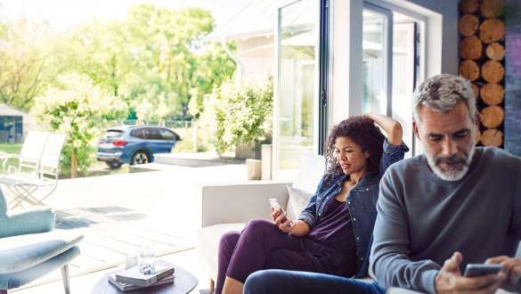 Accedere tramite Remote Services e My BMW App alla BMW Una coppia accede da casa via My BMW App e Remote Services alla BMW