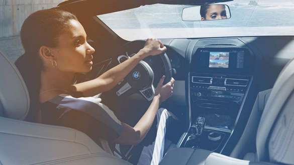 BMW In-Car Experiences Una donna si rilassa durante la guida nella propria BMW con In-Car Experiences