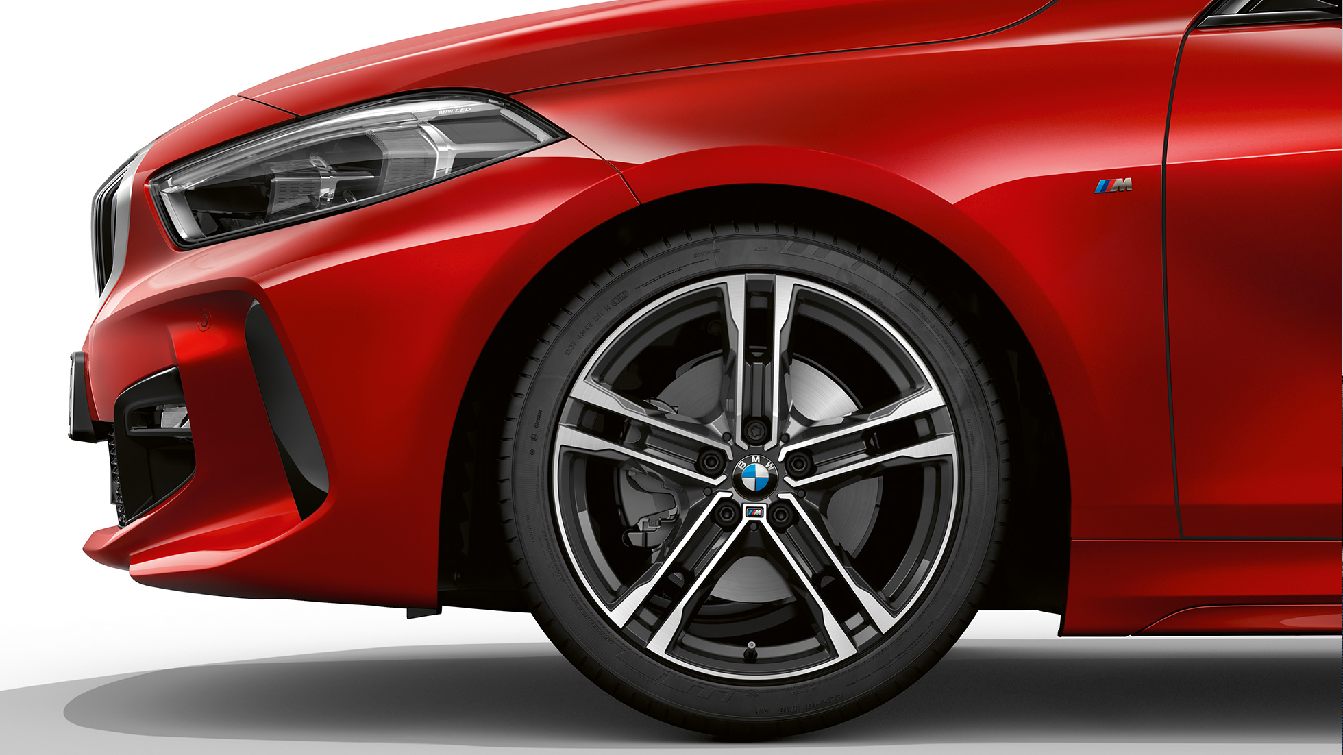 BMW Serie 1, Versione M Sport, vista laterale/frontale F40. BMW Serie 1, Versione M Sport in Melbourne Red metallizzato, vista laterale/frontale con cerchio in lega leggera da 17" M, styling a doppi raggi nº 550 M bicolore F40.