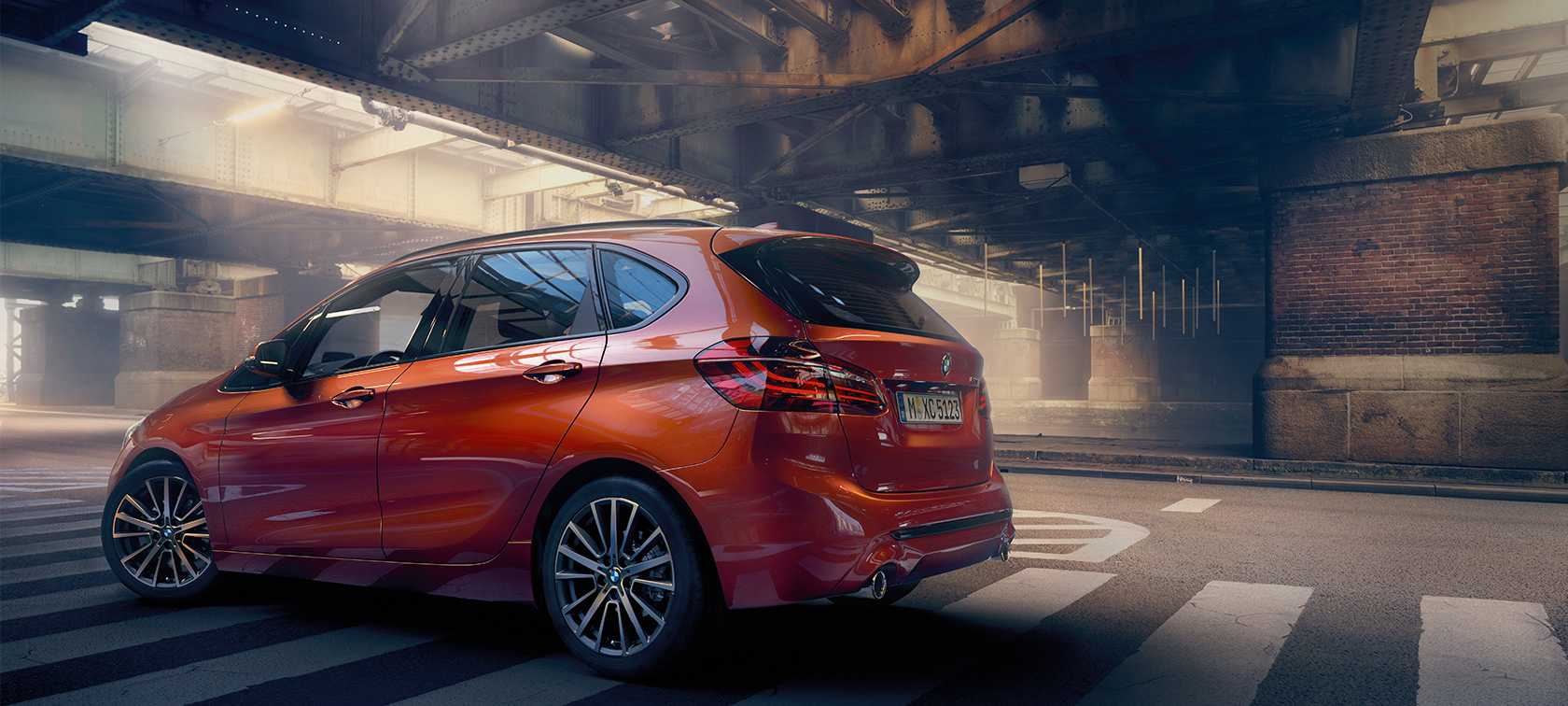 Vista laterale della BMW Serie 2 Active Tourer F45 BMW Serie 2 Active Tourer F45 Facelift 2018 Sunset Orange metallizzato vista laterale da ferma in un padiglione