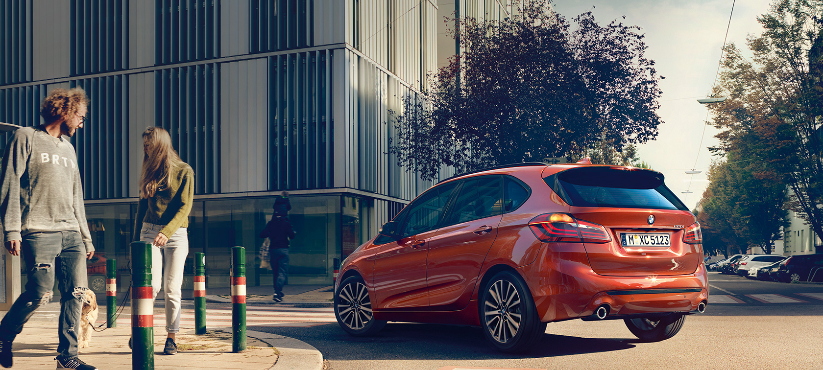 Vista posteriore a tre quarti della BMW Serie 2 Active Tourer 220i F45 BMW Serie 2 Active Tourer 220i F45 Facelift 2018 Sunset Orange metallizzato vista posteriore a tre quarti in movimento su strada
