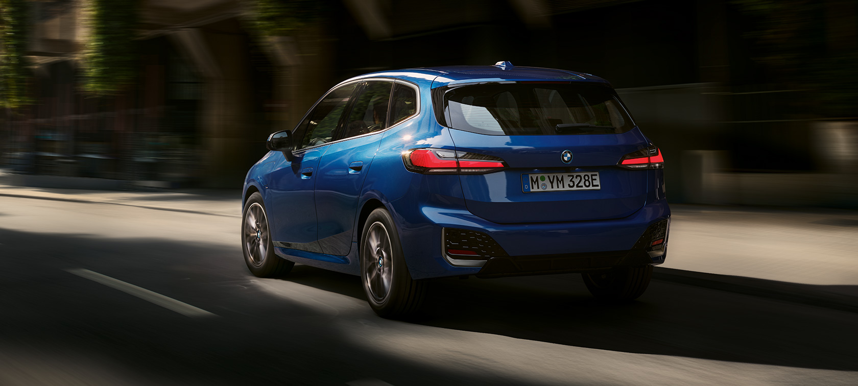 Nuova BMW Serie 2 Active Tourer 230e ibrida Plug-in U06 2021 in movimento in città Nuova BMW Serie 2 Active Tourer 230e ibrida Plug-in U06 2021 M Portimao Blue metallizzato vista posteriore a tre quarti in movimento in città