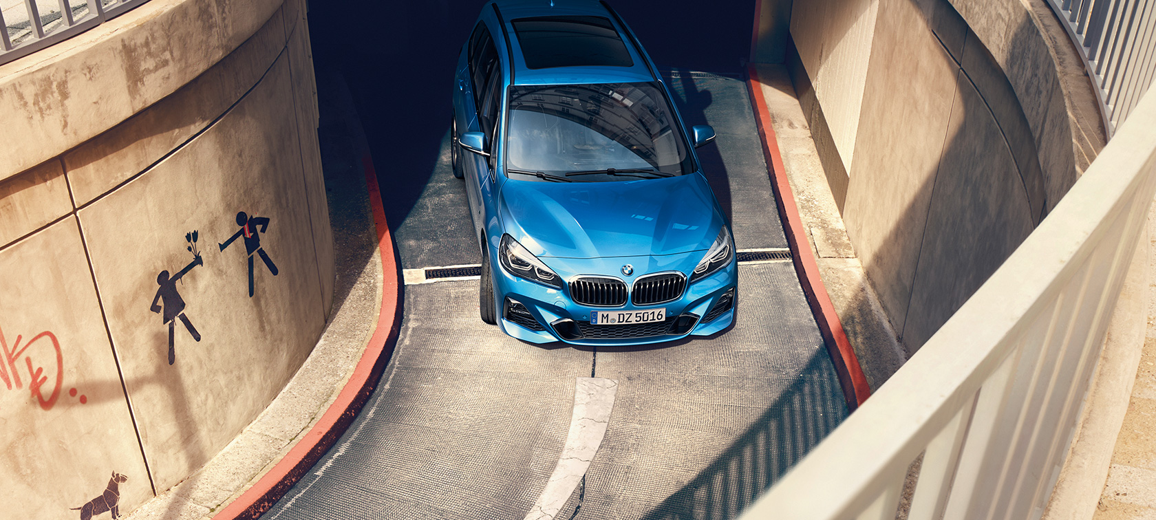 BMW Serie 2 Gran Tourer in movimento in un autosilo F46 BMW Serie 2 Gran Tourer F46 Misano Blue metallizzato con prospettiva a volo di uccello in movimento in un autosilo