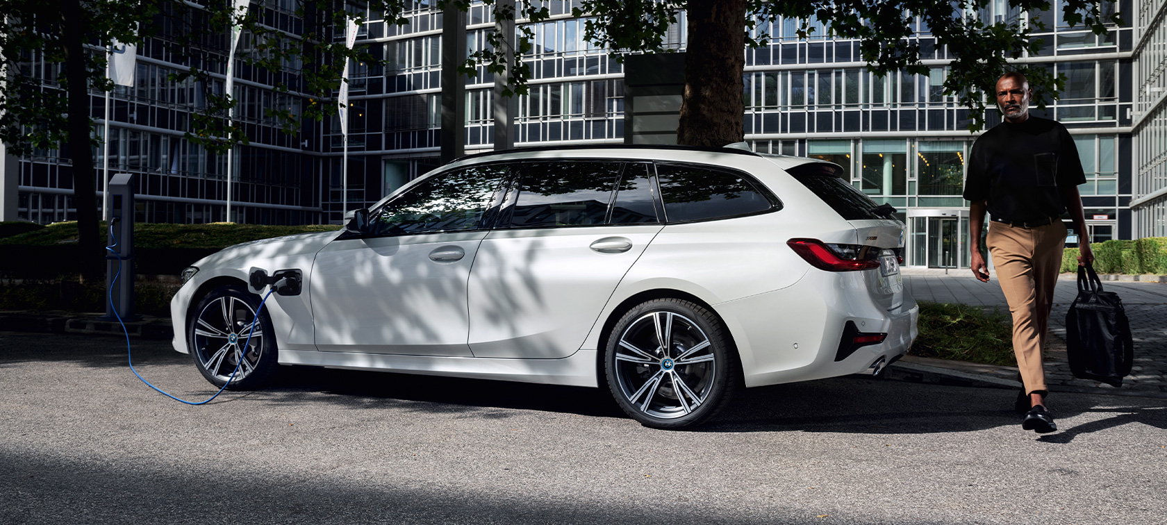 BMW Serie 3 Touring ibrida Plug-in 2021 G21 Vista laterale a tre quarti in ricarica BMW Serie 3 Touring ibrida Plug-in 2021 G21 Vista laterale a tre quarti in ricarica con modella