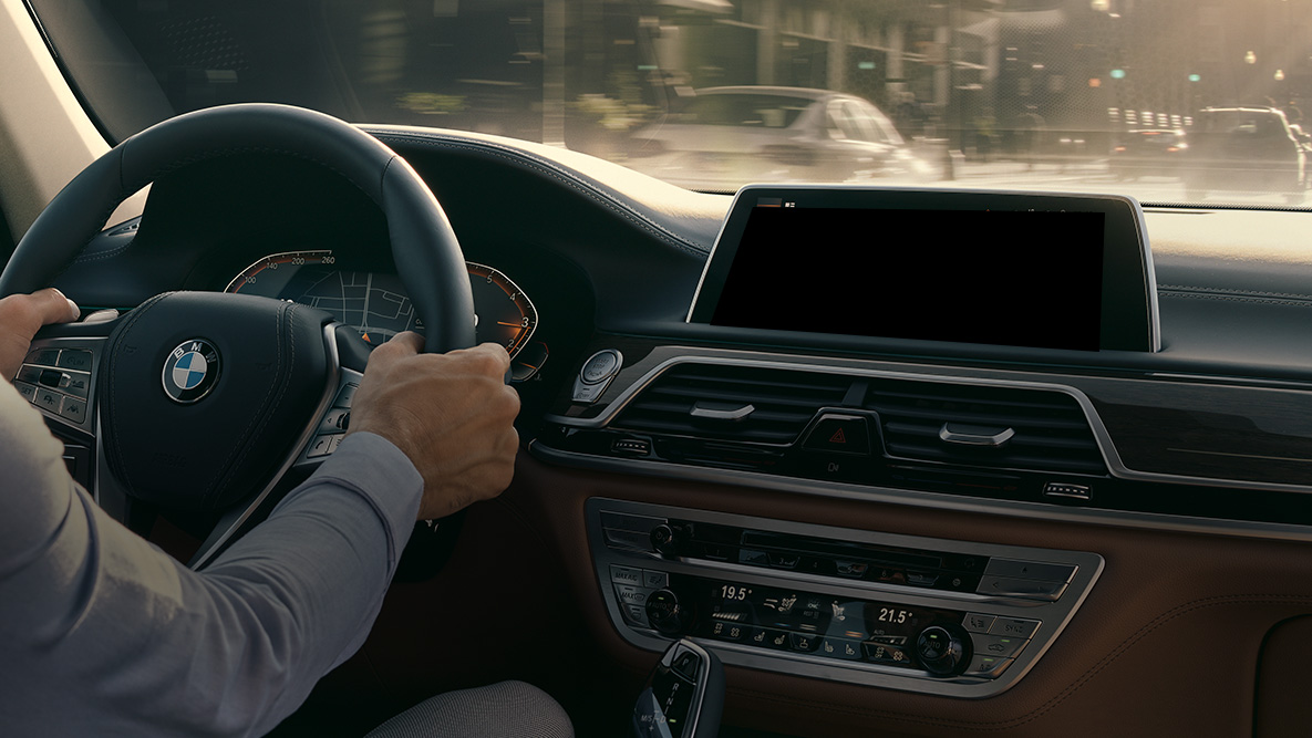 BMW Intelligent Personal Assistant BMW Intelligent Personal Assistant: Uomo alla guida in BMW, primo piano del Live Cockpit Professional