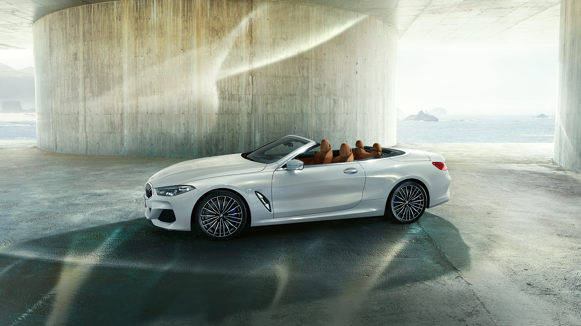 Nuova BMW M850i xDrive in Mineral White metallic, vista laterale con capote in tessuto aperta G14. Nuova BMW M850i xDrive in Mineral White metallic, vista laterale con capote in tessuto aperta G14.