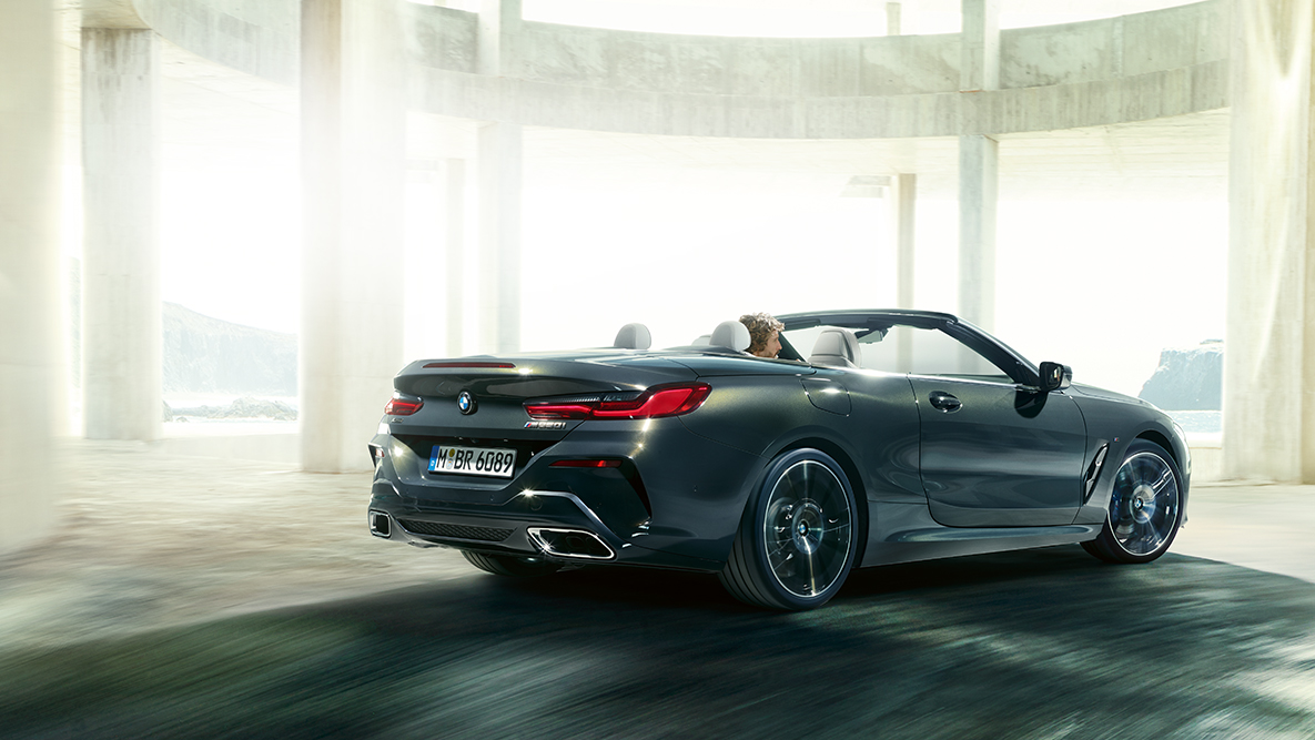 BMW M850i xDrive con capote aperta, in movimento, vista laterale. BMW M850i xDrive con capote aperta, in movimento, vista laterale.