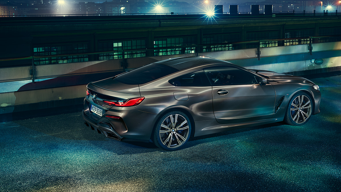 Ripresa laterale da ferma della BMW Serie 8 Coupé. Ripresa da ferma laterale della BMW Serie 8 Coupé con allestimento BMW Individual di notte su sfondo urbano.