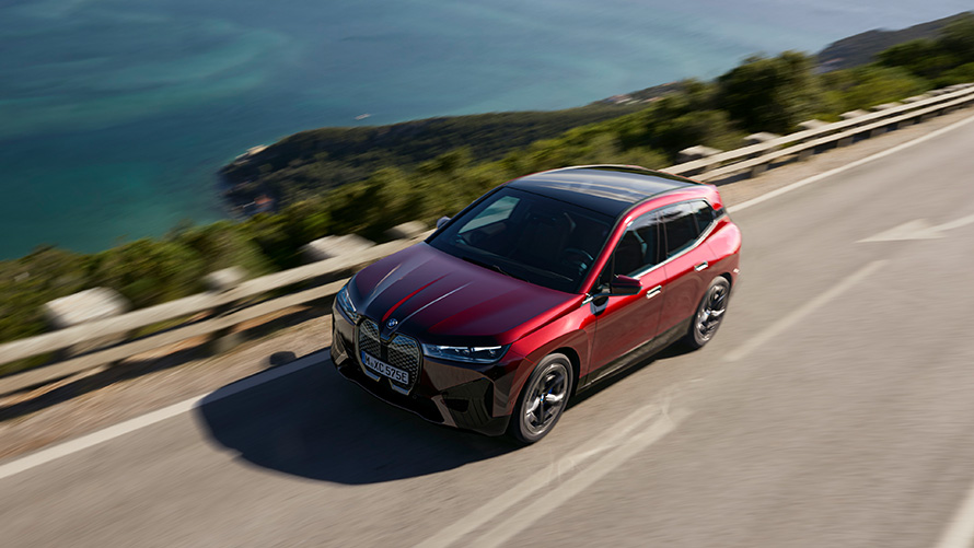 SUV elettrico BMW iX i20 BMW iX xDrive50 Performance SUV elettrico BMW iX i20 2021 SUV BMW iX xDrive50 Aventurine Red in movimento su strada Performance