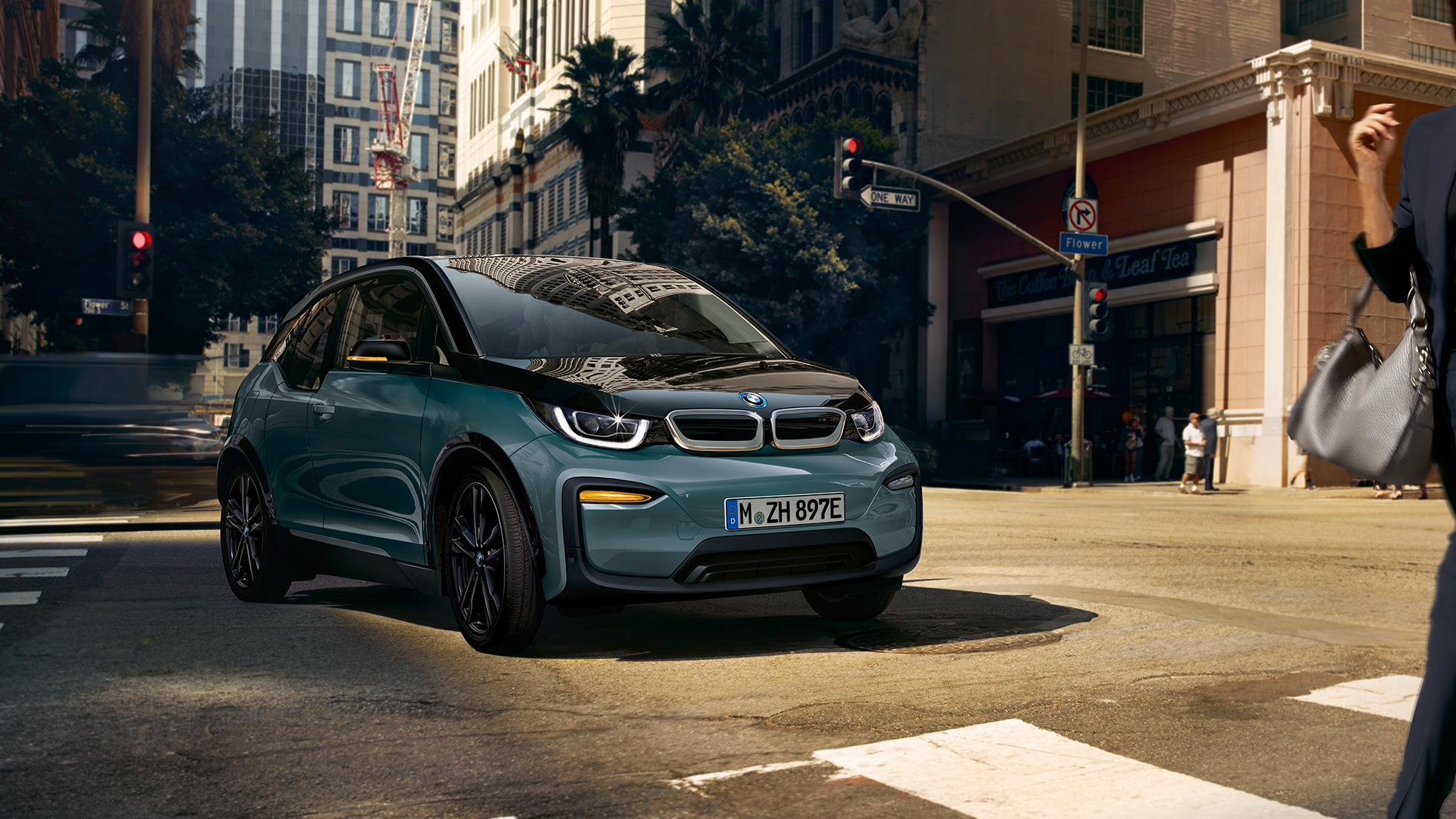 BMW i3 2018 vista anteriore a tre quarti in viaggio I01 BMW i3 I01 2018 Jucaro Beige con profilo in Frozen Grey metallizzato vista anteriore a tre quarti in viaggio su sfondo urbano