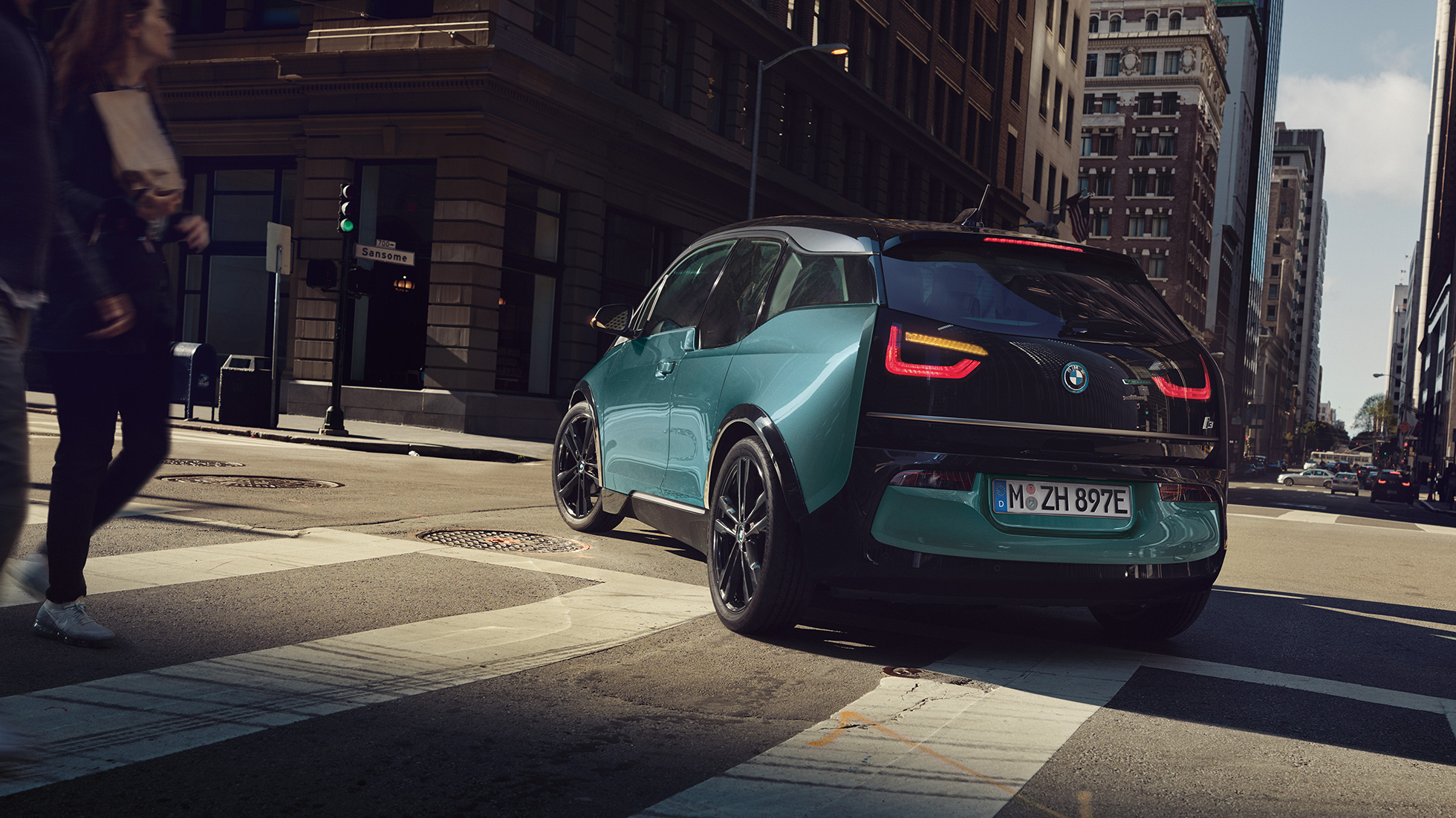 BMW i3 2018 vista posteriore a tre quarti in viaggio I01 BMW i3 I01 2018 Jucaro Beige con profilo in Frozen Grey metallizzato vista posteriore a tre quarti in viaggio su sfondo urbano