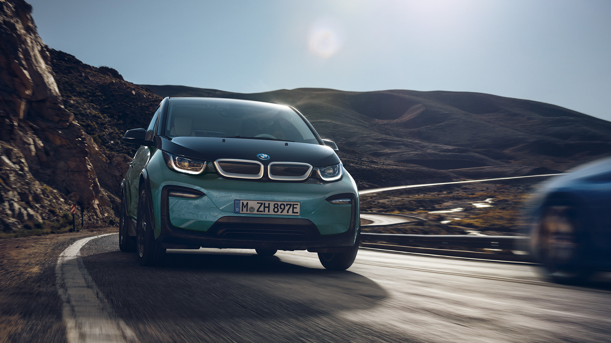 BMW i3 2018 vista laterale in viaggio I01 BMW i3 I01 2018 Jucaro Beige con profilo in Frozen Grey metallizzato vista laterale in viaggio su sfondo urbano
