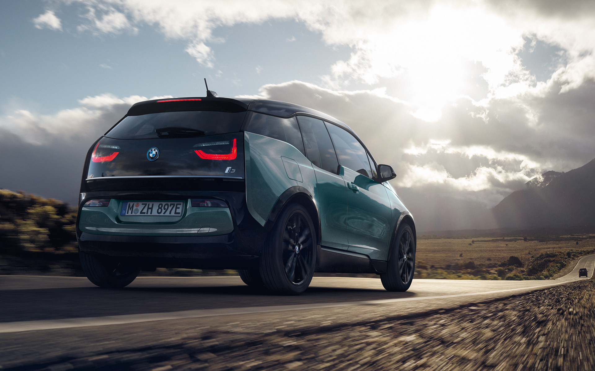 BMW i3 I01 2018 Blue Ridge Mountain con profilo in Frozen Grey metallizzato vista posteriore a tre quarti in viaggio su una strada provinciale
