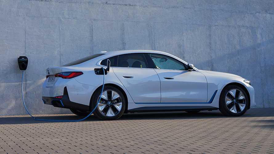 Vista laterale con BMW Wallbox BMW i4 eDrive40 G26 2021 BMW i4 eDrive40 G26 2021 Mineral White Vista laterale davanti a casa con stazione di ricarica BMW Wallbox