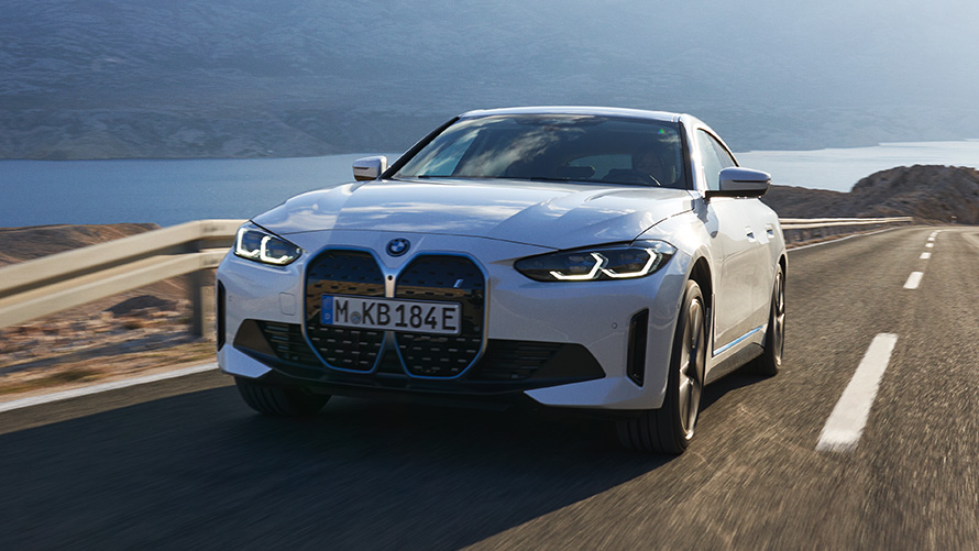 Vista anteriore a tre quarti della BMW i4 eDrive40 G26 2021 in movimento BMW i4 eDrive40 G26 2021 Mineral White vista anteriore a tre quarti in movimento