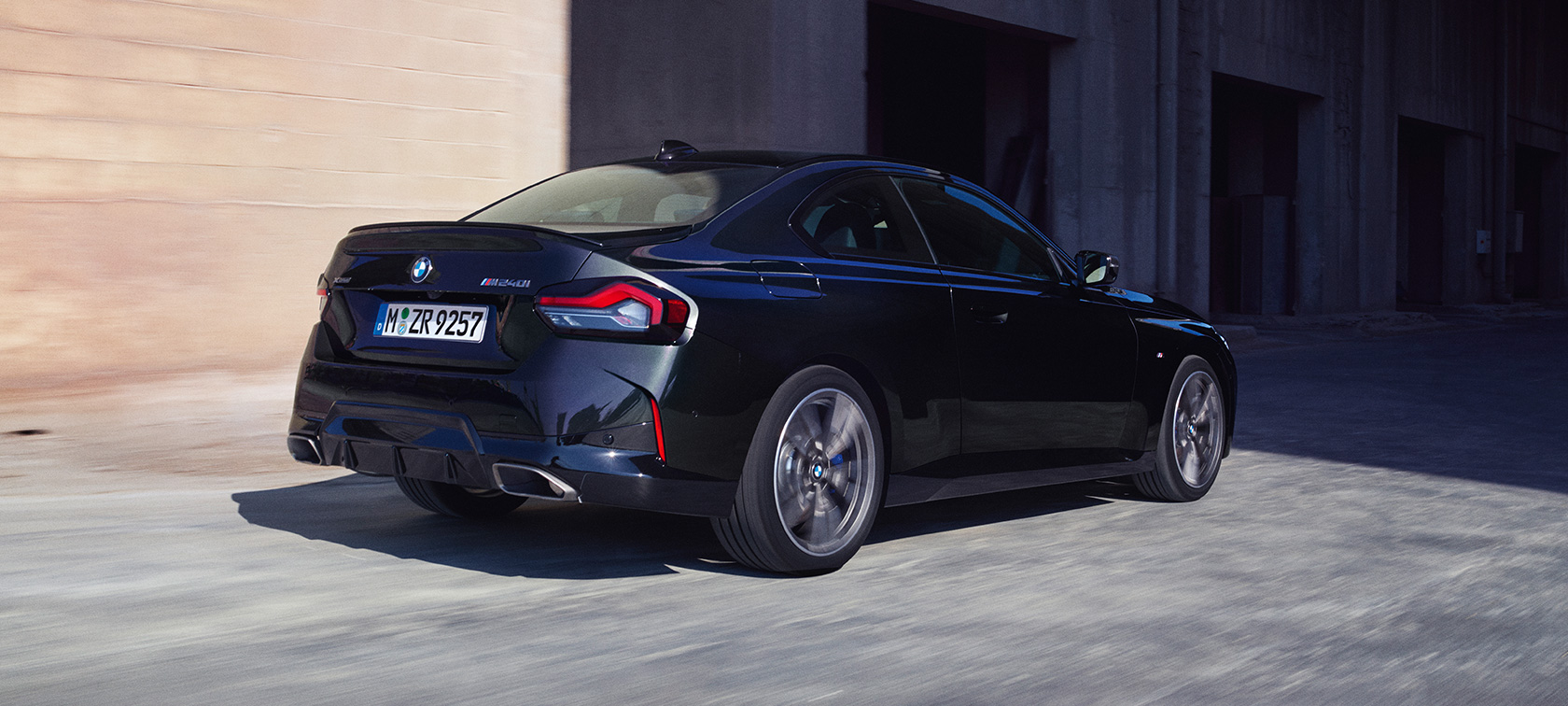 Vista posteriore a tre quarti della BMW M240i xDrive Coupé G42 2021 BMW M240i xDrive Coupé G42 2021 Black Sapphire metallizzato Vista posteriore a tre quarti in viaggio
