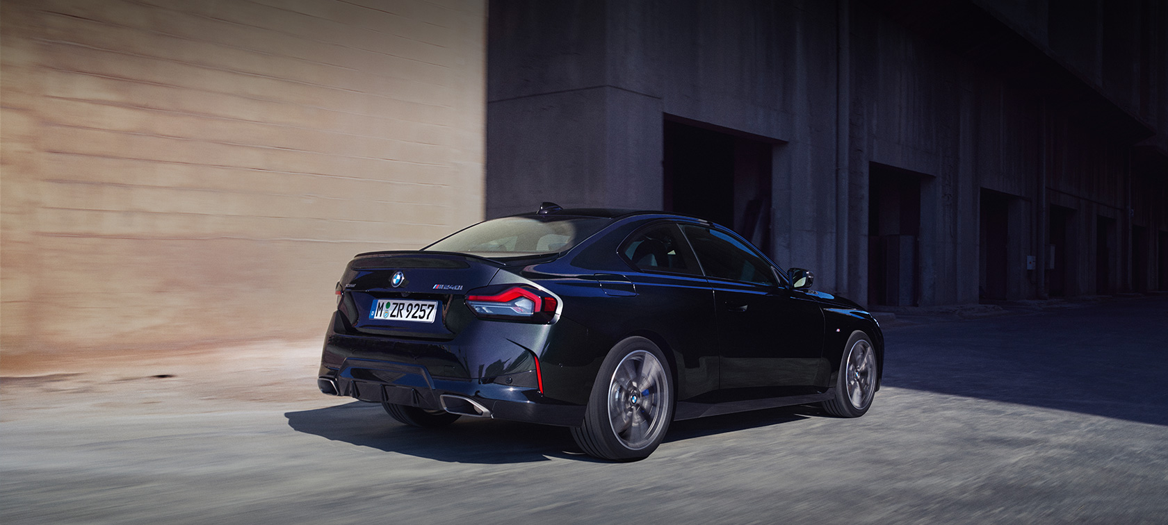 BMW M240i xDrive Coupé G42 2021 Vista posteriore a tre quarti in viaggio BMW M240i xDrive Coupé G42 2021 Black Sapphire metallizzato Vista posteriore a tre quarti in viaggio